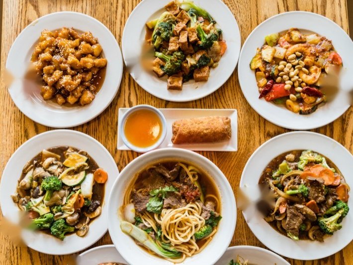 Autumn Court family-style catering spread with egg roll and eight dishes